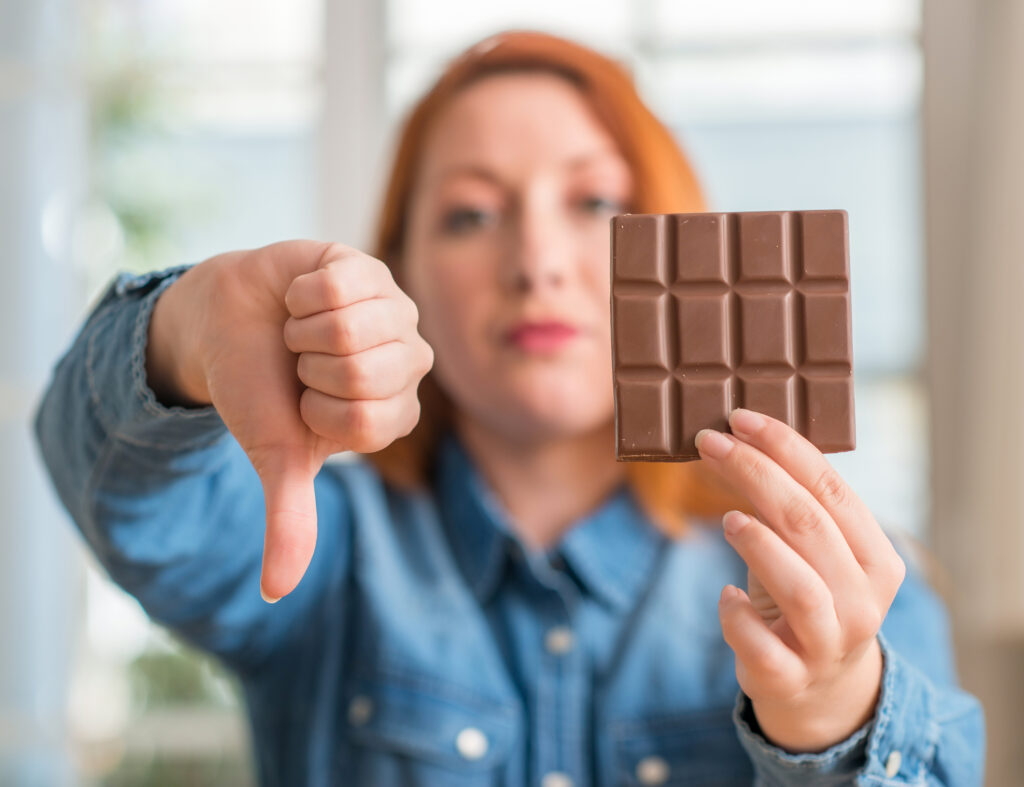 Une jeune femme qui tend une tablette de chocolat, le pouce baissé